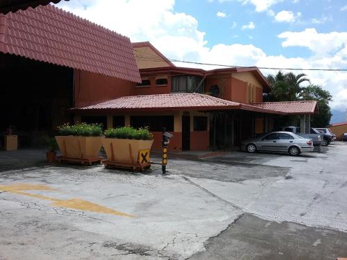 a building with two large flower pots in a parking lot at Hotel Cibeles Resort in Heredia