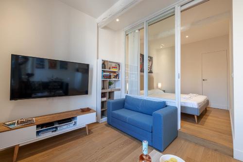 un salon avec un canapé bleu et une télévision dans l'établissement Apartment Matisse 100m Near The Sea - Happy Rentals, à Antibes