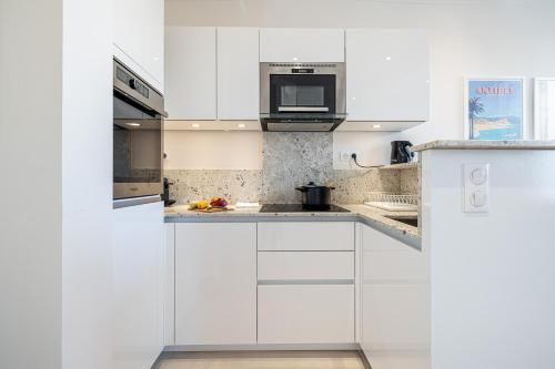 une cuisine blanche avec des armoires blanches et un micro-ondes dans l'établissement Apartment Matisse 100m Near The Sea - Happy Rentals, à Antibes