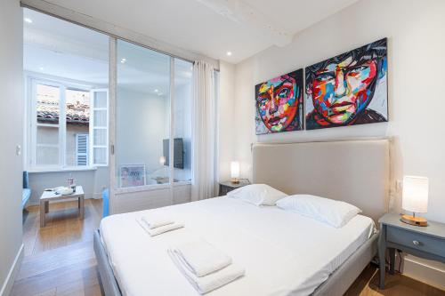 une chambre avec un lit avec un tableau sur le mur dans l'établissement Apartment Matisse 100m Near The Sea - Happy Rentals, à Antibes