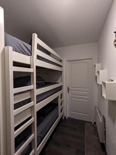 Ce lit superposé blanc se trouve dans un dortoir doté d'une porte. dans l'établissement Refuge AuRoiSud, à La Bresse