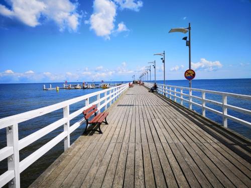 a wooden pier with benches on the water at Angel Sea Hill Apartment in Mechelinki