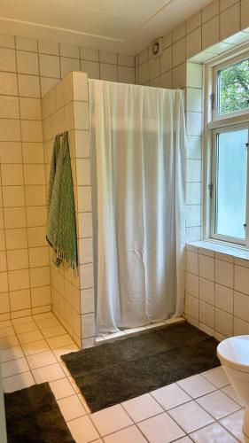 a shower with a white shower curtain in a bathroom at Aabenterp in Vrå
