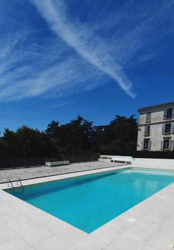 une piscine bleue avec un bâtiment en arrière-plan dans l'établissement LE156 Studio Cosy Thermes, Piscine & Box Privé, à Aix-les-Bains