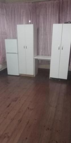 two white cabinets in a room with a wooden floor at Restinpeace accommodation in Pietermaritzburg