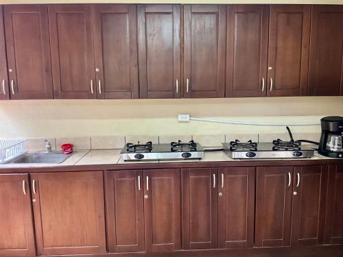 a kitchen with wooden cabinets and a stove top at Casitas de la Paz in Coco