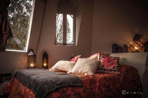 a bedroom with a bed with pillows and two windows at Villa Nao in Roxton Falls
