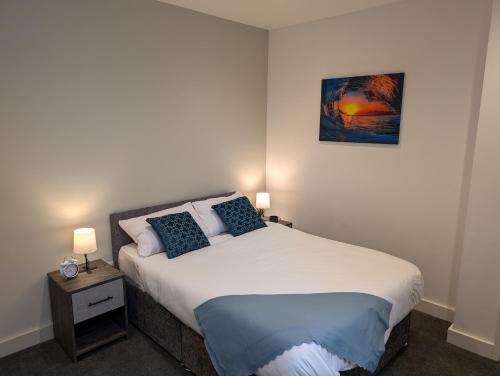 a bedroom with a large bed with two blue pillows at City Centre Premier Executive Apartments in Sunderland