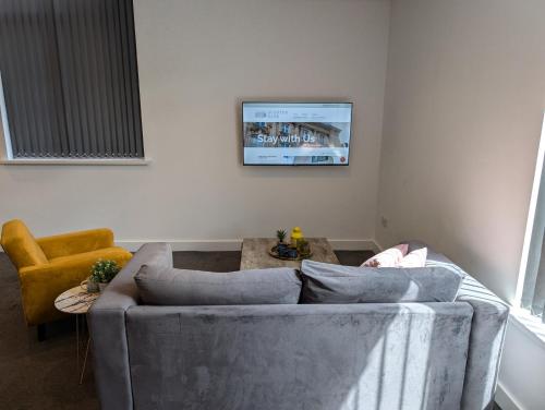 a living room with a couch and a tv on the wall at City Centre Premier Executive Apartments in Sunderland
