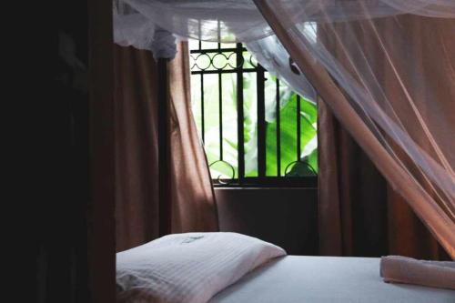 a bedroom with a bed with a window at Jangwani River View Suits in Mto wa Mbu