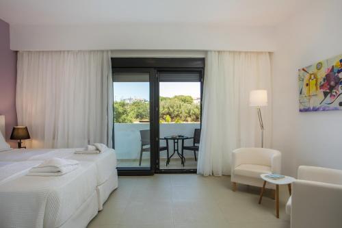 a hotel room with two beds and a table and chairs at Villa Melia in Koskinou