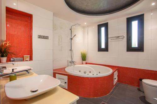 a bathroom with a tub and a toilet and a sink at Villa Melia in Koskinou