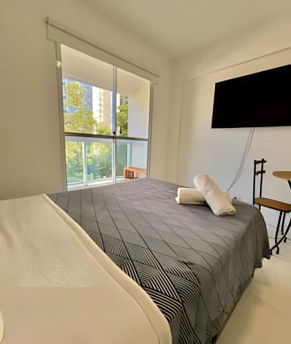 a bedroom with a bed and a flat screen tv at Studio Vertentes in Sao Paulo