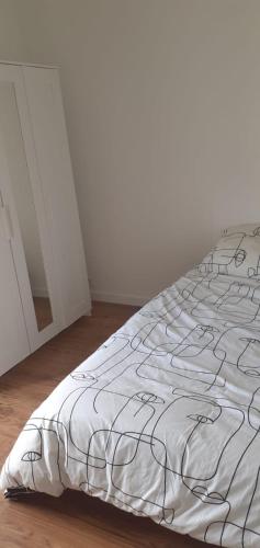 - un lit blanc avec une couverture noire et blanche dans l'établissement Chambre proche de paris et Roissy, à Persan