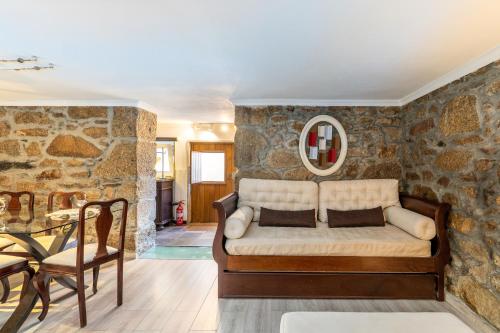 a living room with a couch against a stone wall at BABhouse Loja do Cavalo - Coração do Douro in São João da Pesqueira