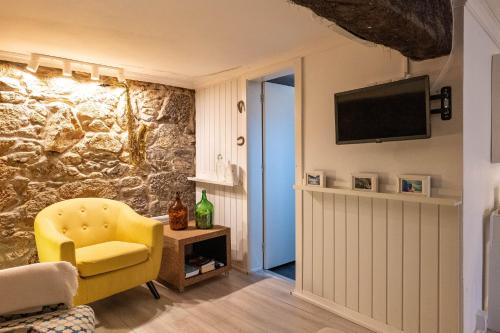 a living room with a yellow chair and a television at BABhouse Loja do Cavalo - Coração do Douro in São João da Pesqueira