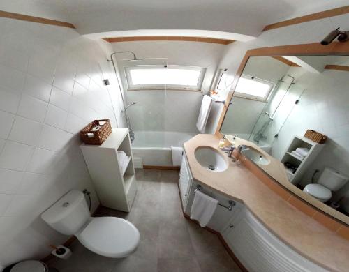 een badkamer met een wastafel, een toilet en een spiegel bij Apartamento 90m2 com vista mar - Albufeira in Albufeira
