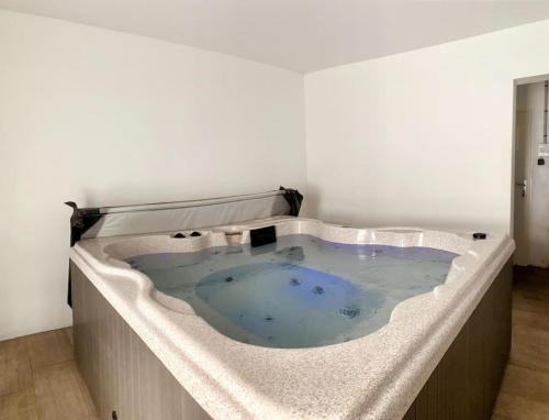 un jacuzzi dans une pièce blanche dans l'établissement Maison avec jacuzzi 10 personnes, à Locquénolé