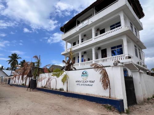a white building with palm trees in front of it at Nungwi Beach Front in Nungwi