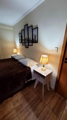 a bedroom with a bed and a table with two lamps at HOTEL ESTÂNCIA - ESTACIONAMENTO GRATUITO ROTATIVO - Vagas Limitadas in Poços de Caldas