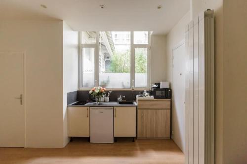une cuisine avec un évier et une fenêtre dans l'établissement Charming studio in a courtyard in Paris, à Paris