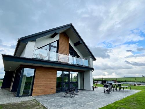 a house with a balcony with tables and chairs at Butter Chill House - Dom na Kaszubach in Masłowo