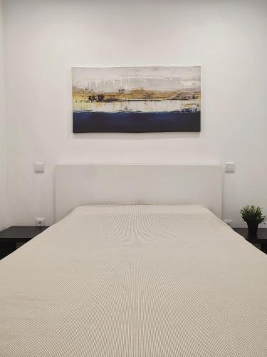 a bedroom with a white bed and a painting on the wall at Seventy House By Furabeach in Furadouro