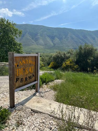 a sign on the side of a road with mountains in the background at Kantina & Ferma Dukat in Vlorë