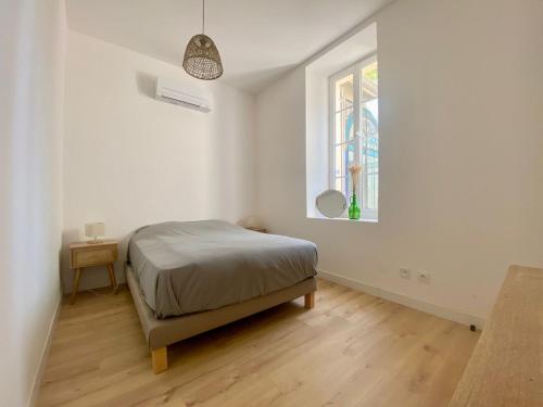 a white bedroom with a bed and a window at Appartement de standing dans une bastide Aixoise in Aix-en-Provence
