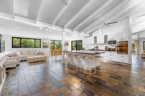an open kitchen and living room with white walls and wooden floors at Sleep 9 @ Secluded Farmstay 12min to Coffs Harbour in Bonville