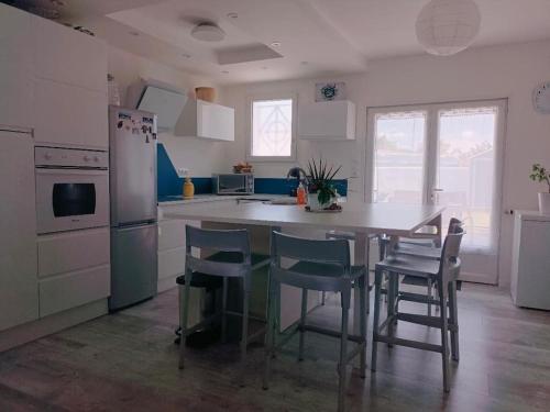 une cuisine avec une table, des chaises et un réfrigérateur dans l'établissement Maison plain pied 2 chambres, à Fouras