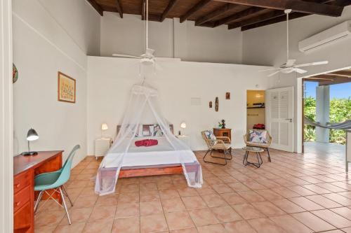 a bedroom with a bed and a desk and chairs at Villa San Sebastian Curaçao in Fontein