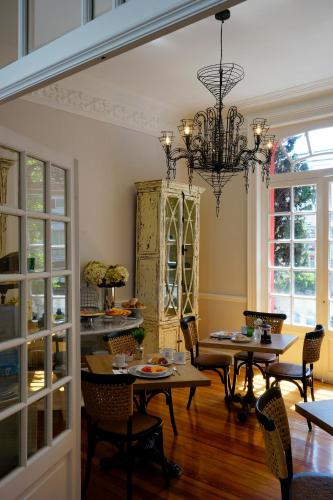 una sala da pranzo con tavoli e sedie e un lampadario di Casa Goliana La Roma a Città del Messico