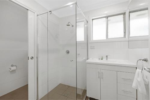 a white bathroom with a shower and a sink at Prickly Pear Stays Jesmond - Short Term Accommodations in Jesmond