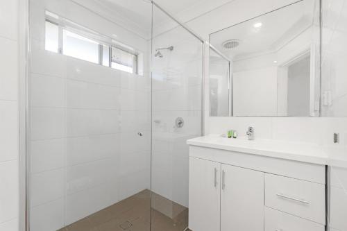 a white bathroom with a shower and a sink at Prickly Pear Stays Jesmond - Short Term Accommodations in Jesmond