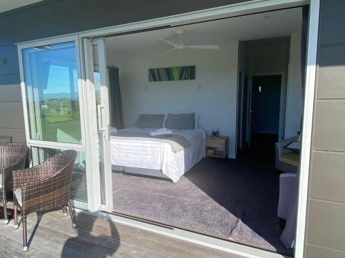 a bedroom with a bed and a sliding glass door at Moko Hiwi Escape Ruakaka - Tūī Suite in Ruakaka
