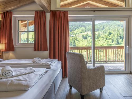 a room with two beds and a chair and a window at Alpen Villa Danica in Mühlbach am Hochkönig