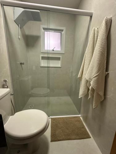a bathroom with a shower with a toilet and a window at Suíte completa em Gramado in Gramado