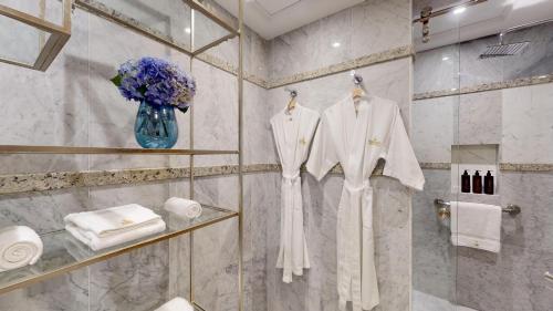 a bathroom with white robes and a vase of flowers at Marquis SkySuites in Mexico City