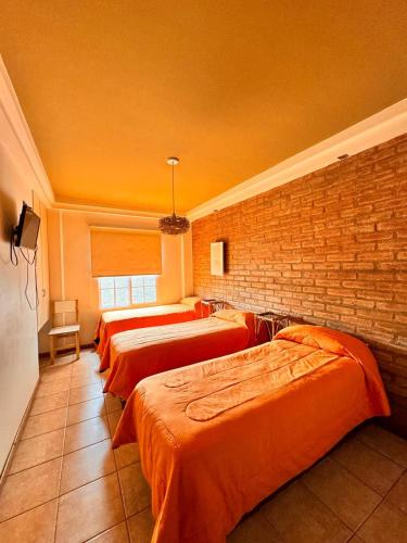 three beds in a room with a brick wall at Hotel Cuesta del Viento in San Juan