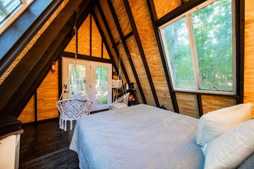 a bedroom in a tree house with a bed and windows at tiny A frame in the woods in Lincoln