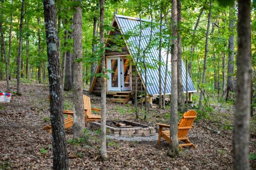 a cabin in the woods with two chairs and trees at tiny A frame in the woods in Lincoln