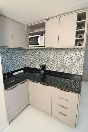 a kitchen with white cabinets and a black counter top at Tropical Executive Flat 1307 With View in Manaus