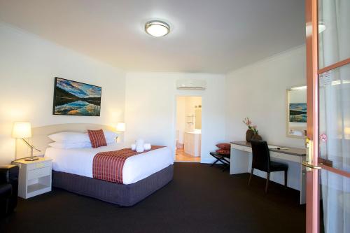 a hotel room with a bed and a desk at Bowen Inn Motel in Lithgow