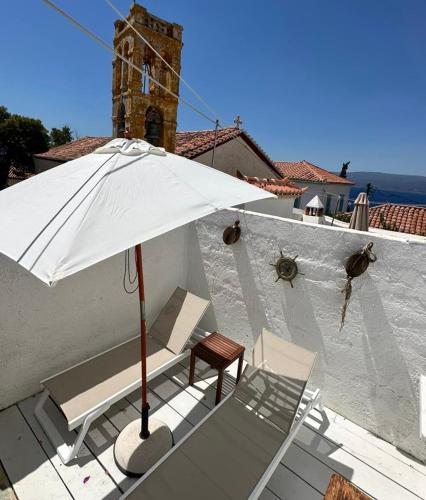a white umbrella and chairs on a patio at Louisa’s View in Hydra