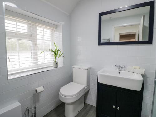 a white bathroom with a toilet and a sink at The Cottage in Stratford-upon-Avon