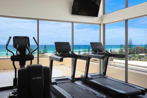 a gym with three cardio machines in front of a window at Paradise Centre Apartments managed by Gchs in Gold Coast