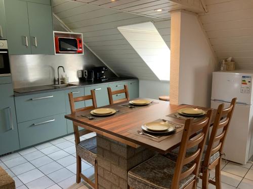 a kitchen with a wooden table with chairs and a refrigerator at LinZn vakantiehuis in Wuustwezel