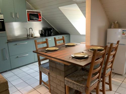 a kitchen with a wooden table with chairs and a refrigerator at LinZn vakantiehuis in Wuustwezel