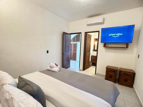 a bedroom with a bed with a tv on the wall at Hotel Tres Santos in Troncones